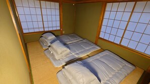 A traditional Japanese-style room with tatami flooring, a low bed with a futon, and shoji screens. - Hotel1800 (Minamiuonuma)