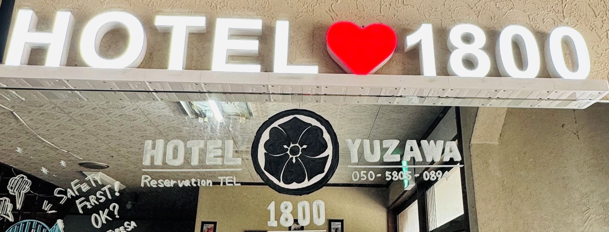 Et hotelskilt med teksten 'HOTEL 1800' og 'YUZAWA' samt et telefonnummer.