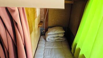 Quarto pequeno e estreito com uma cama de solteiro e uma placa indicando o número 211-D.