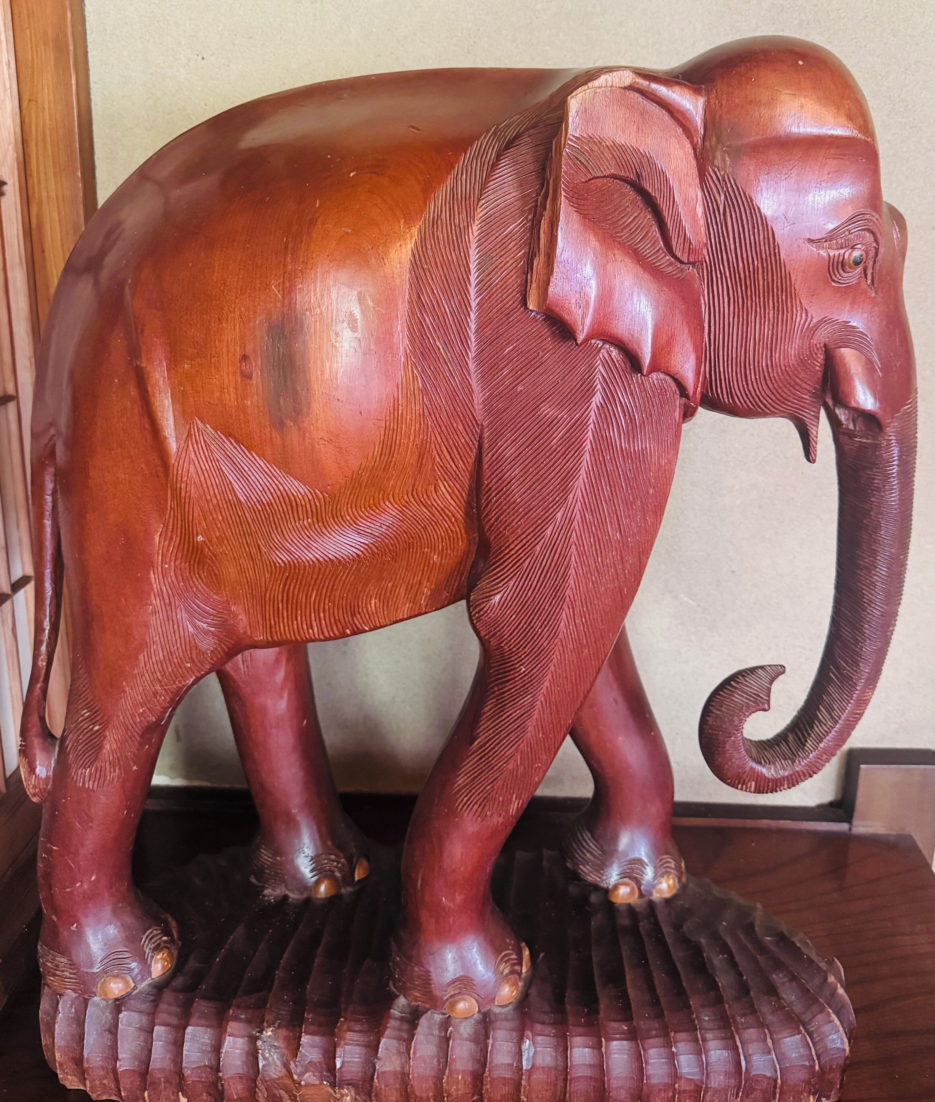 A wooden elephant sculpture with detailed carvings on its trunk and legs.