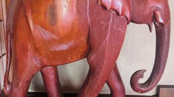A wooden elephant sculpture with detailed carvings on its trunk and legs.