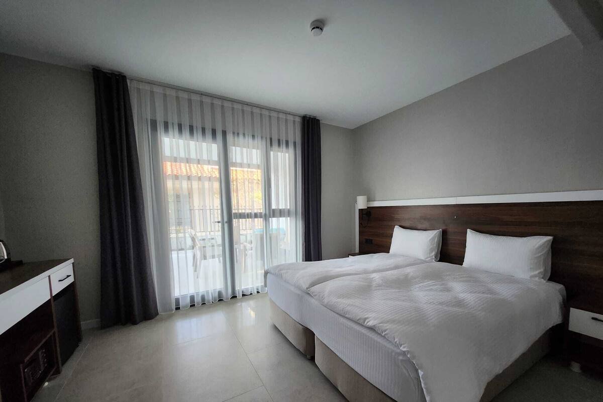 A hotel room with a large bed, a desk, and a view through the window.