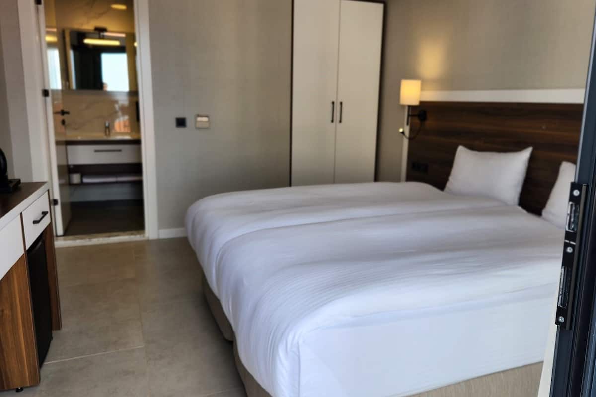 A hotel room with a large bed, a wardrobe, a desk, and a bathroom visible through an open door.