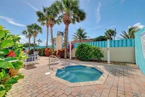 A swimming pool with a tiled deck, surrounded by palm trees and a fence. - 404 Ocean View Condo (Avalon Beach Club Assn) (Fort Pierce)
