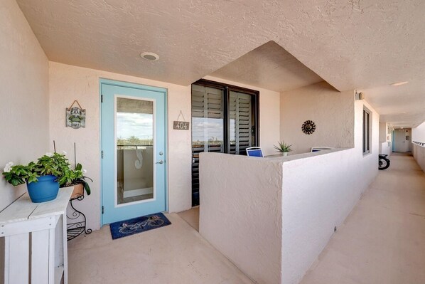 A hallway with a blue door, a number sign, and a potted plant. - 404 Ocean View Condo (Avalon Beach Club Assn) (Fort Pierce)