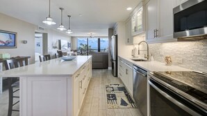 A modern kitchen with a large island, stainless steel appliances, and a view to the outdoors. - 404 Ocean View Condo (Avalon Beach Club Assn) (Fort Pierce)