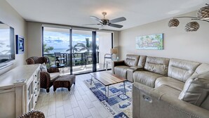A spacious living area with a balcony, a sofa, a coffee table, and a TV. - 404 Ocean View Condo (Avalon Beach Club Assn) (Fort Pierce)