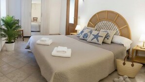 Ein Schlafzimmer mit einem großen Bett, einer Topfpflanze, einem Holzkopfstück und einem gewebten Korb.