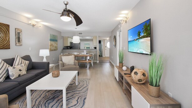 Uma sala de estar moderna com sofá, mesa de centro e televisão na parede.
