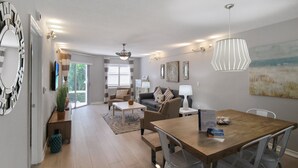 Uma sala de estar moderna com uma mesa de jantar de madeira, sofás e um quadro grande na parede.