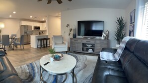 A modern living room with a leather sofa, a round coffee table, and a TV. - Newly renovated Lantana FL condo, All new luxury furnishings, 2 miles from Ocean (Lantana)