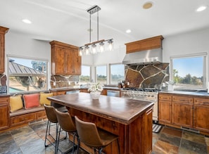 A spacious kitchen with a large island, wooden cabinets, and a stone backsplash.