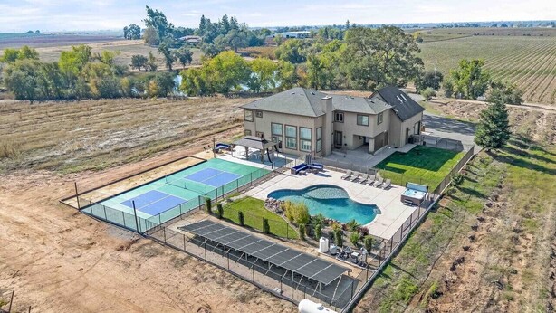 Una casa grande con piscina, canchas de tenis y un patio vallado.