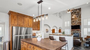Una cocina moderna con una isla grande, electrodomésticos de acero inoxidable, armarios de madera y una pared decorativa de piedra.