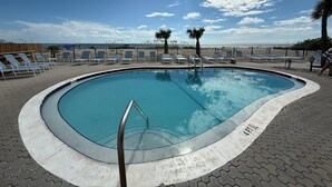 En pool med liggestole og udsigt til stranden.