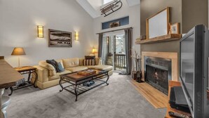 A living room with a sofa, coffee table, fireplace, and a television. - 2BD Condo w/Ski Run Views & Hot Tub Access (Park City)