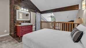A bedroom with a wooden accent wall, a white bed, a red dresser, and a ceiling fan. - 2BD Condo w/Ski Run Views & Hot Tub Access (Park City)
