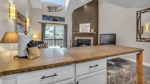 A modern kitchen with a large island, white cabinetry, and a fireplace. - 2BD Condo w/Ski Run Views & Hot Tub Access (Park City)