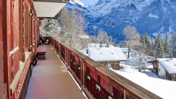 Een houten gebouw met een balkon met uitzicht op een besneeuwd berglandschap.