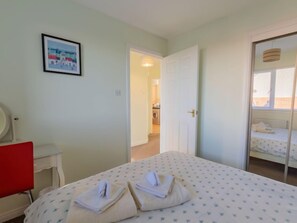Een hotelkamer met een bed, een bureau, een stoel en een lijst met foto op de muur.