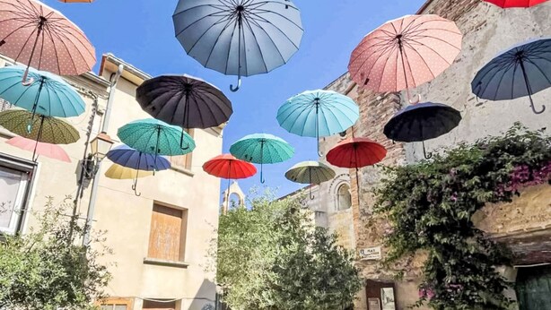 A courtyard with multiple colorful umbrellas suspended from the ceiling.