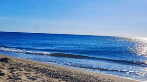 A beach with clear blue water and a sandy shore.