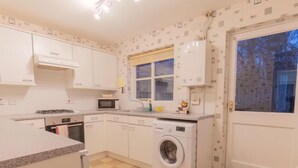 A compact kitchen with a washing machine, a microwave, and a sink. - Cedar House by Interhome (Inverness)