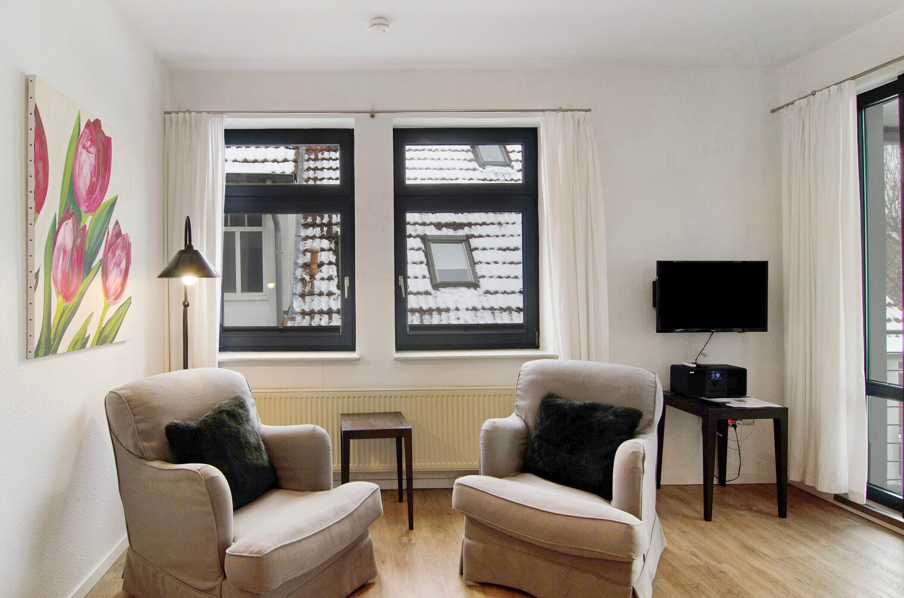 A living room with two armchairs, a TV, and a radiator.