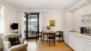 Una cocina moderna con comedor, televisor de pantalla plana y puerta de vidrio corrediza que da a un balcón.
