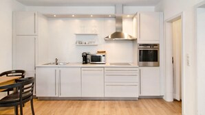 Una cocina moderna con armarios blancos, microondas, cafetera y horno.