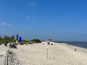 Una playa con cielo despejado, una torre de salvavidas y algunas personas.