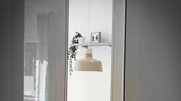 Ein Zimmer mit einem Holzespeisetisch, Stühlen, einer Pendelleuchte und einem Blumentopf.