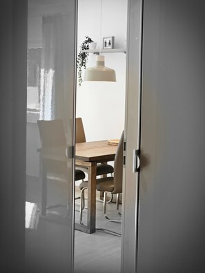 Une pièce comprenant une table à manger en bois, des chaises, un luminaire suspendu et une plante en pot.