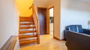 Un escalier menant à la cuisine, un salon avec un canapé bleu et un plancher en bois.