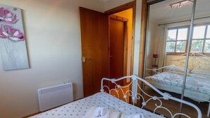 Une chambre à coucher avec un lit, un radiateur, une porte en bois et une grande fenêtre.