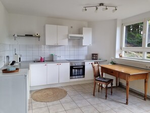Ett modernt kök med vita skåp, en spis och en matplats med ett träbord och stolar.