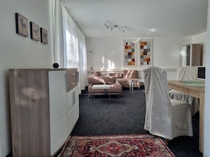 Ett modernt vardagsrum med en soffa, ett soffbord, en tv och en mönstrad matta.