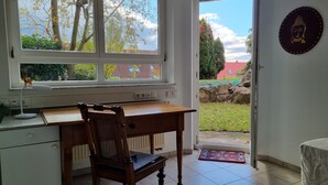 A room with a desk, chair, and a view of the garden through a window.