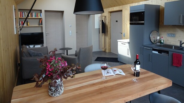 Una cucina moderna con zona pranzo, soffitto in legno ed elettrodomestici integrati.
