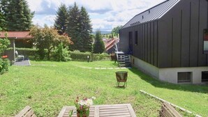 Un prato verde con un tavolo e sedie di legno, un edificio in metallo e un recinto di legno.