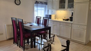 Un comedor con una mesa, sillas y un reloj en la pared.
