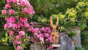 Un jardín con flores rosadas y una escultura de madera.