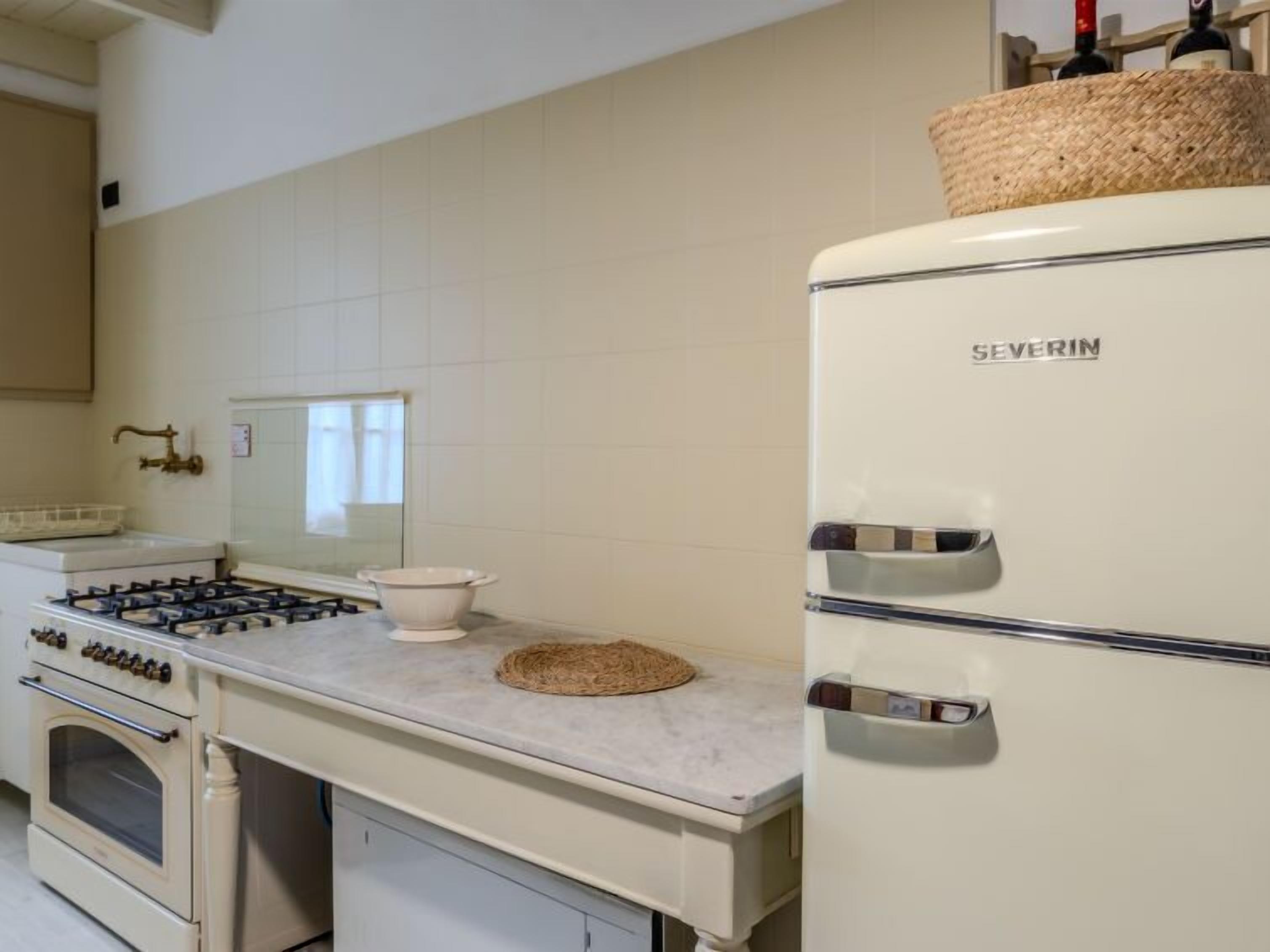 A kitchen with a white stove, a white refrigerator, and a white sink.