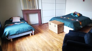 A room with two beds, a chair, a fireplace, and a radiator. - Chez sandrine (Gray-la-Ville)