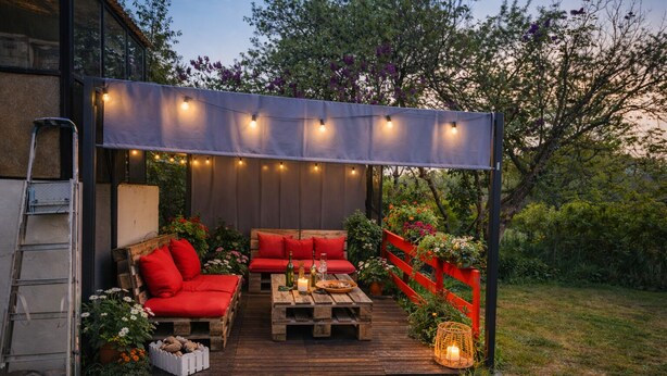 An outdoor patio with wooden furniture, string lights, and a red fence. - Chez sandrine (Gray-la-Ville)
