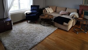 A living room with a blue armchair, a beige sofa, a wooden coffee table, and a white rug. - Chez sandrine (Gray-la-Ville)
