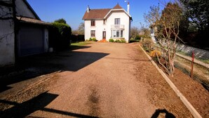A two-story house with a front driveway, a garage, and a fenced garden area. - Chez sandrine (Gray-la-Ville)