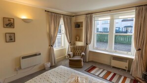 A bedroom with a bed, a chair, a radiator, a window with curtains, and a view of the outside. - Old Lodge by Interhome (Inverness)