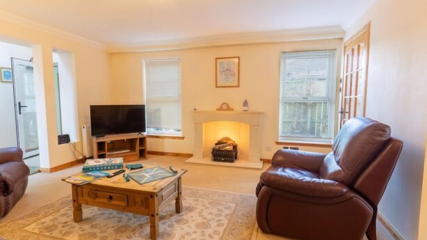 A living room with a fireplace, a television, and a leather armchair. - Lodge Road by Interhome (Inverness)