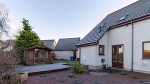 A residential property with a gravel driveway, a wooden deck, and a small wooden structure. - Evergreen House by Interhome (Inverness)